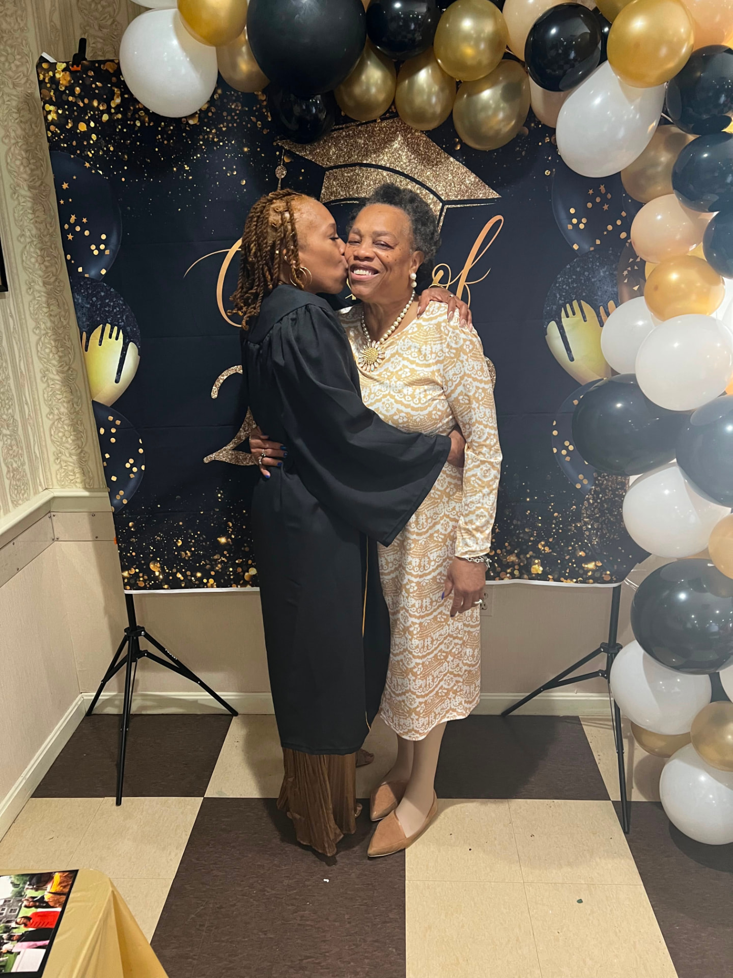Debra in graduation attire embracing a loved one at a celebration