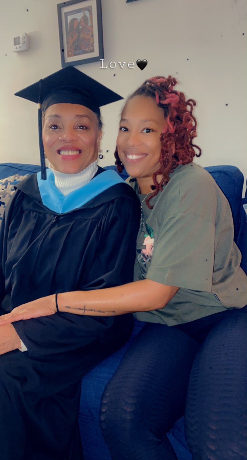 Debra in graduation regalia sharing a joyful moment with a family member